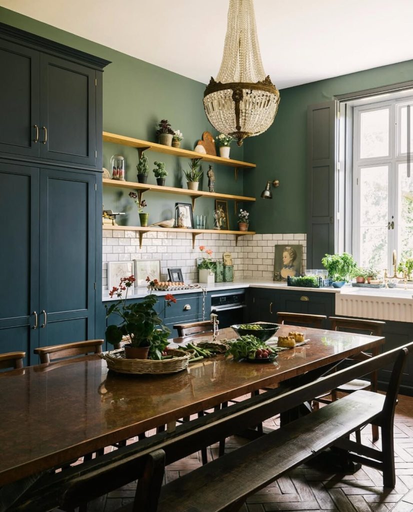 A classic English kitchen with gentlest green walls paired with dark cabinets, and a long table 